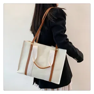 Détail du sac fourre-tout en toile avec doubles poignées en cuir marron et coutures