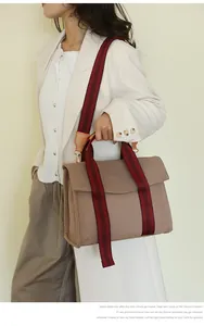 Detail of khaki canvas tote with striped woven strap and leather trim contrast