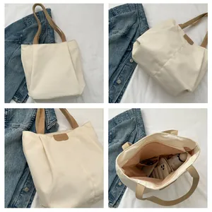 Detail view of large canvas tote bag with pink interior compartments and leather label