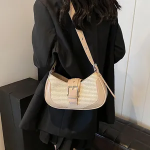 Detail of beige woven underarm bag featuring silver buckle and adjustable strap