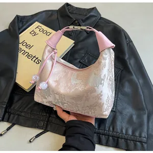 Detailed view of pink embroidered brocade fabric and metal snap on Chinese handbag