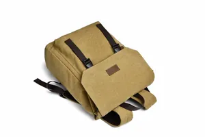Detail view of khaki canvas backpack featuring flap cover with leather patch and buckle straps