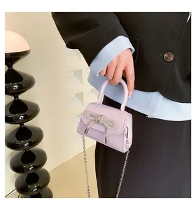 Detail of lavender mini bag with rhinestone bow and delicate metal chain strap