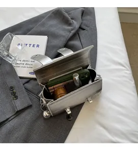 Vue intérieure du sac argenté à motif crocodile montrant l'espace pour téléphone et parfum