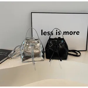 Detail of silver metallic and black glossy pleated drawstring bucket bags on white steps
