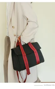 Detail of a black canvas tote with red striped straps paired with a beige blazer set