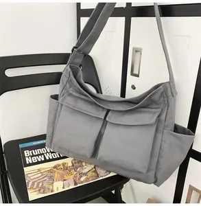 Detailed view of grey canvas messenger bag with large front pockets and adjustable strap