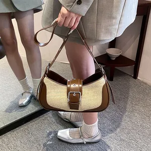 Detail of hobo bag featuring straw woven fabric and dark brown leather with metal buckle