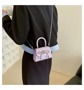 Detail of light purple mini bag with a sparkling rhinestone bow and silver chain strap