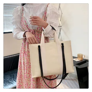 Détail d'un cabas en toile avec bandoulières en cuir noir et poignées beige crème