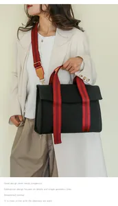 Detail of black canvas tote bag featuring stylish red striped wide shoulder strap design