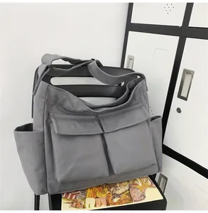Detail of dark grey canvas messenger bag featuring large front pockets and rugged utility style