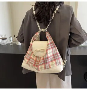 Detail eines karierten Rucksacks mit cremefarbener Schleife und gemischter Stoffstruktur