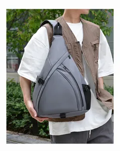 Close-up of gray teardrop chest bag showing multi-compartment zippers and mesh pocket