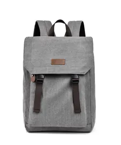 Detailed view of gray canvas backpack with brown strap buckles and leather patch accent