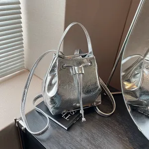 Detailed shot of silver textured bucket bag featuring drawstring closure and top handle