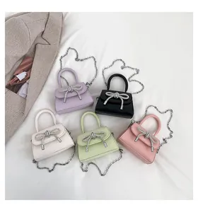 Top view of mini crossbody bags with rhinestone bows in five pastel colors and chain straps