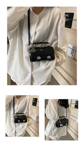 Détail du sac bandoulière en PU noir brillant avec ferrures argentées et poignée