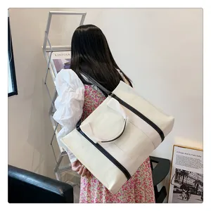 Grand sac cabas en toile crème avec liserés noirs présenté dans une scène de style de vie