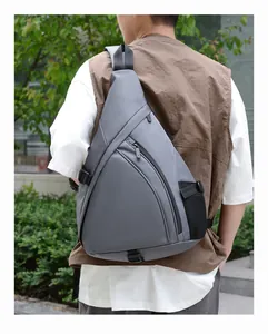 Outdoor shot of the gray triangular crossbody bag showing the side mesh bottle pocket