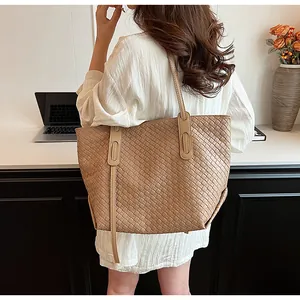 Dettaglio della borsa tote intrecciata color cammello con spalline lunghe in ufficio minimal