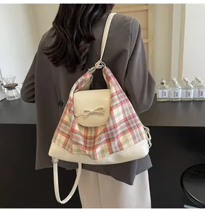 Detail eines rosa karierten Rucksacks mit Schleife, getragen auf einem grauen Sakko