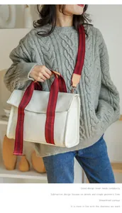 Close-up of cream canvas tote bag with red-brown striped handles and adjustable strap