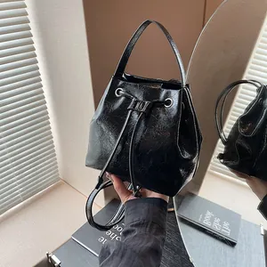 Detail of black wrinkled leather bucket bag showing drawstring closure and silver eyelets
