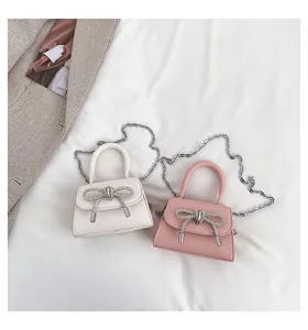 Top view of mini cream and pink girls handbags with rhinestone bows and chain straps