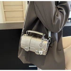 Détail du sac cylindre argenté avec motif crocodile et pendentif boule métallique chic