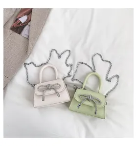Detail view of mini handbags featuring rhinestone bows and metallic chain straps