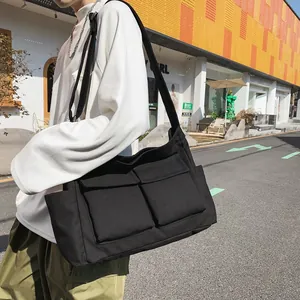 Black canvas messenger bag with large capacity and multi-pocket design on city street