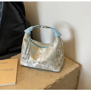 Detailed close-up of embroidery pattern and blue leather handle on the dumpling bag