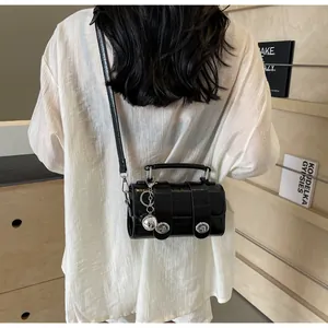 Détail d'un sac bandoulière en similicuir noir avec pendentif sphère argentée sur modèle