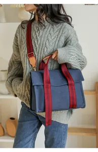 Close-up of blue canvas tote featuring red striped handles and yellow leather trim