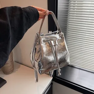 Detail of silver metallic bucket bag featuring wrinkled texture and drawstring closure