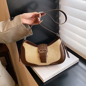 Detail of woven straw and brown leather bag with metallic buckle and adjustable strap