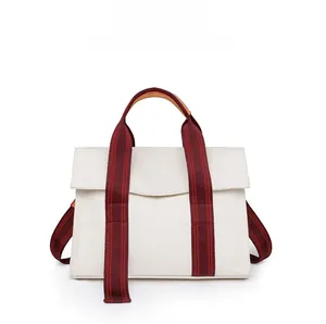 Front view of beige canvas tote bag with red and brown striped straps and leather handle
