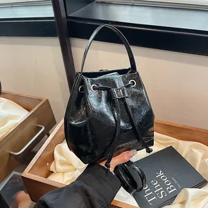 Detailed close-up of retro black crinkled patent leather bucket bag with silver eyelets
