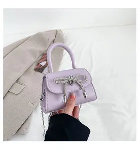 Detail of light purple mini girl's bag with rhinestone bow and silver chain strap