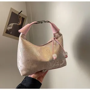 Detailed close-up of pink jacquard fabric handbag with gold Chinese embroidery and silver clasp
