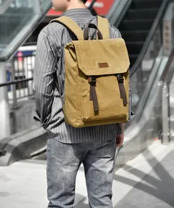 Outdoor shot of a mustard yellow canvas backpack with brown straps and flap closure