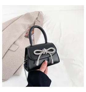 Detail of black mini handbag with rhinestone bow and silver chain strap for girls