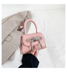 Detailed view of pink mini bag featuring a large rhinestone bow and silver chain strap