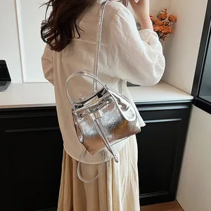 Silver metallic bucket bag with textured pleats worn as a backpack in a modern interior