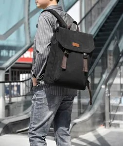 Male model wearing black canvas backpack with flap design and brown straps in city setting