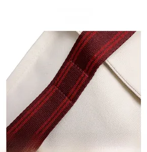 Close-up of reinforced stitching and red-black striped webbing handle on white canvas bag