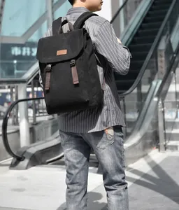 Outdoor shot of the minimalist black canvas backpack with brown leather tag and flap design