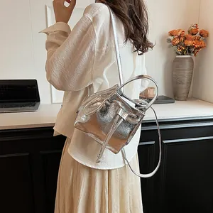 Close-up of a silver metallic bucket bag with drawstring closure and glossy mirror finish