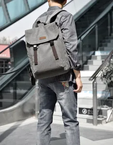 Outdoor view of a grey canvas backpack with brown straps and buckle on modern stairs